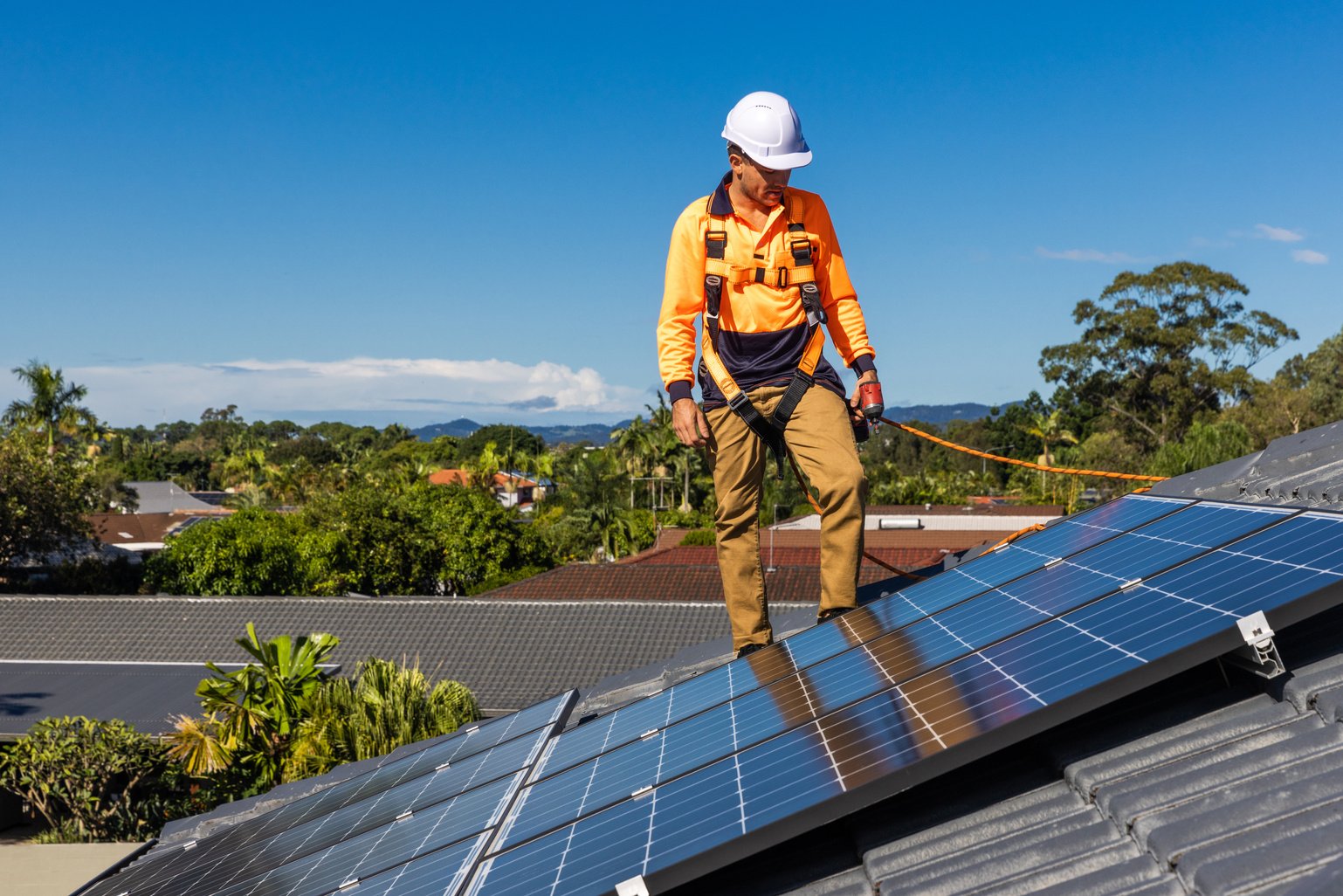 Solar panel technician with drill installing solar panels