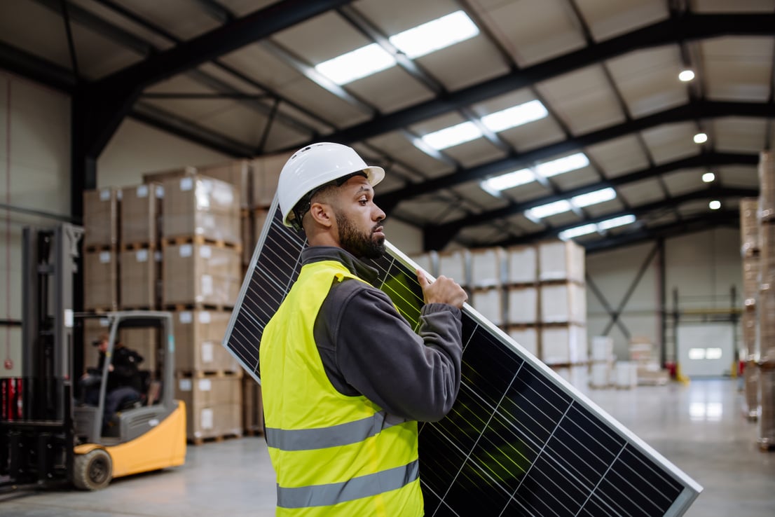 Handsome Worker Carrying Solar Panel in Warehouse, Factory. Solar Panel Manufacturer, Solar Manufacturing.